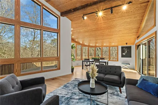 a living room with stainless steel appliances granite countertop a coffee maker a sink and white cabinets with wooden floor
