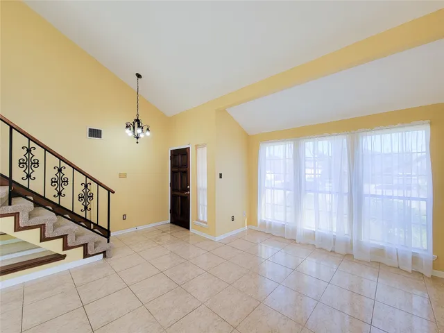 a view of an empty room with chandelier fan