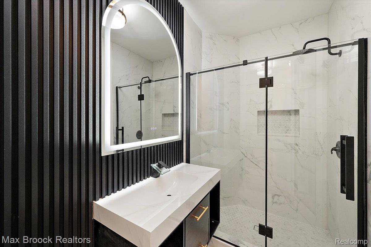4597 Clarkston Road Clarkston, MI 48348 - Photo 39 of 74 Integrated vanity with rectangular basin, arched LED mirror, and black slat wall