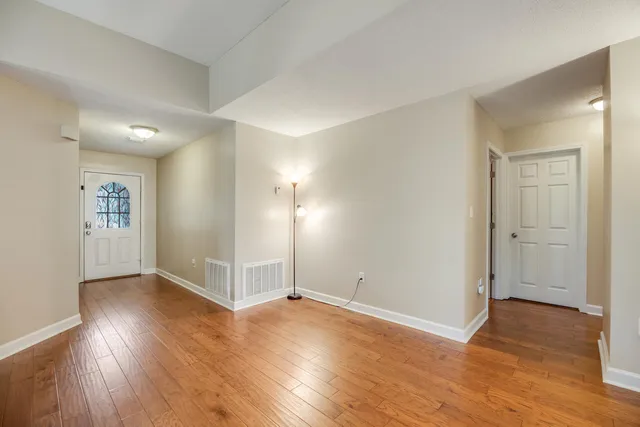 an empty room with wooden floor fireplace and windows