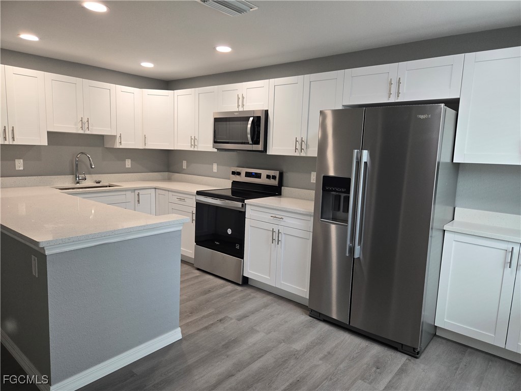 16930 Juanita Avenue Fort Myers, FL 33908 - Photo 4 of 6 a kitchen with stainless steel appliances a refrigerator a stove a sink and white cabinets