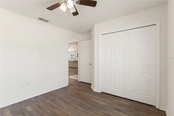 an empty room with wooden floor closet and windows