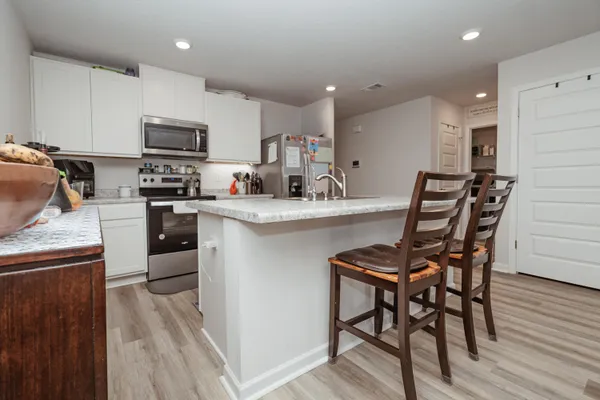 a kitchen with stainless steel appliances kitchen island granite countertop a table chairs sink and cabinets