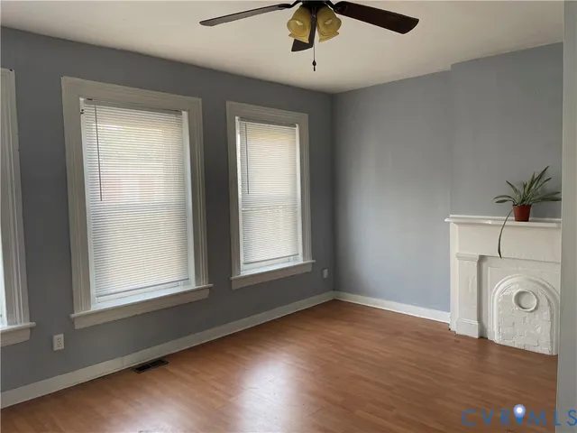 an empty room with wooden floor fan and windows