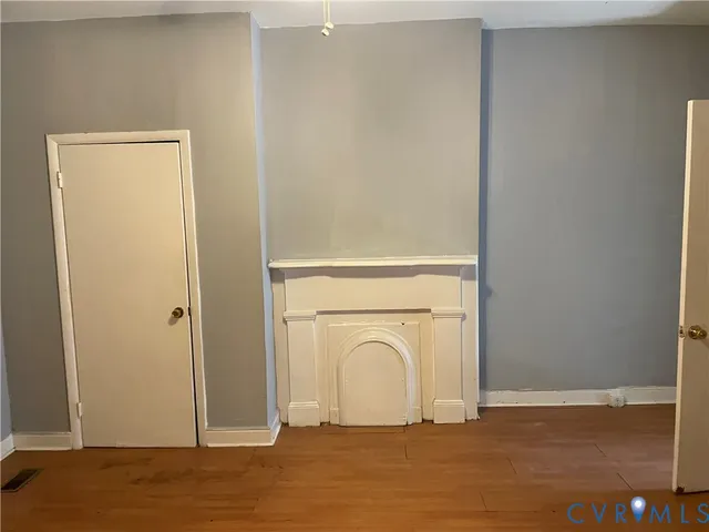 a view of a livingroom with wooden floor and a fireplace