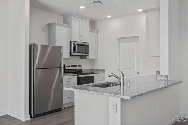 a kitchen with stainless steel appliances granite countertop a refrigerator and a sink