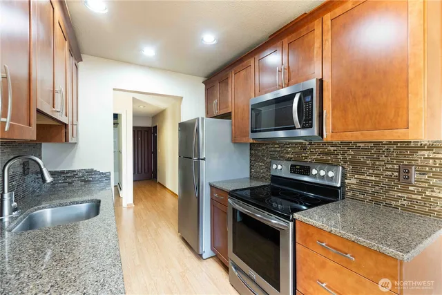 a kitchen with stainless steel appliances granite countertop a sink stove and microwave