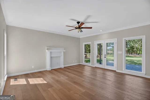 a view of an empty room with a window and wooden floor