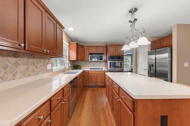 a large kitchen with kitchen island a large counter top space appliances and cabinets