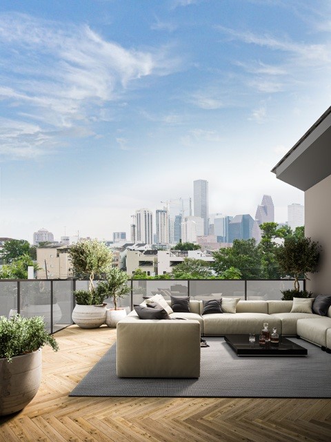 1222 Winter Street Houston, TX 77007 - Photo 9 of 13 This photo showcases a modern rooftop terrace with a spacious seating area and lush planters. The space offers stunning downtown views of a Houston skyline under a clear blue sky, perfect for relaxation and entertaining. Virtually Staged.