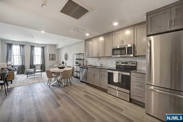 a kitchen with a refrigerator a stove top oven a dining table and chairs with wooden floor