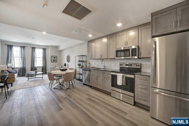 a kitchen with a refrigerator a stove top oven a dining table and chairs with wooden floor