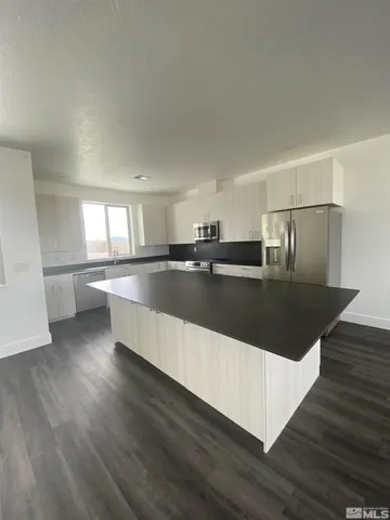 a large kitchen with stainless steel appliances granite countertop a large counter top and wooden floor