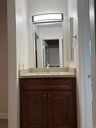 a bathroom with a granite countertop sink a mirror and cabinets