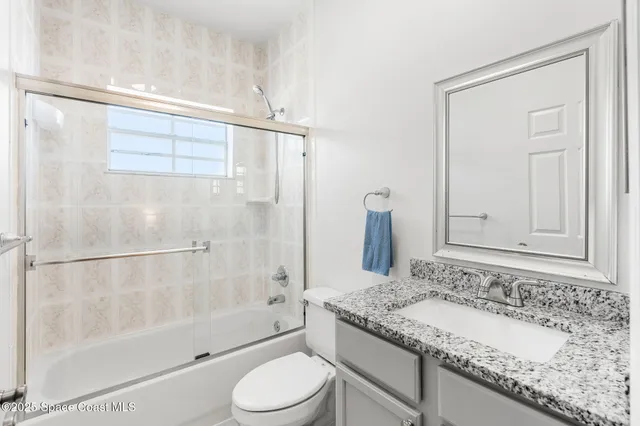 a bathroom with a granite countertop sink a toilet and shower