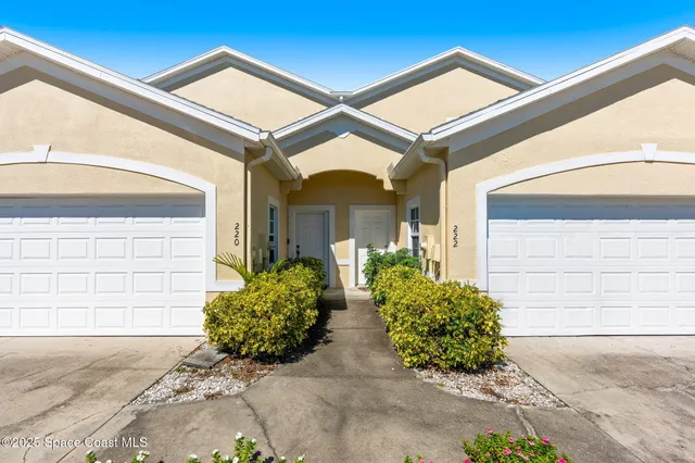 a view of a brick house with large windows and flower plants