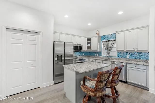 a kitchen with a refrigerator a sink and chairs