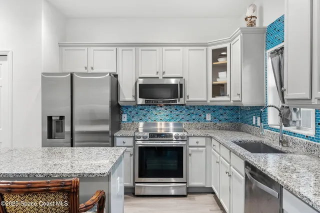 a kitchen with granite countertop a sink stainless steel appliances and counter space