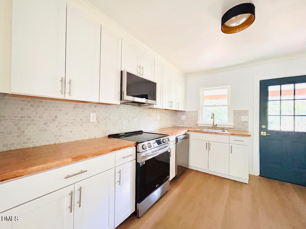 1606 James Street Durham, NC 27707 - Photo 10 of 24 a kitchen with granite countertop a sink a stove top oven and cabinetry