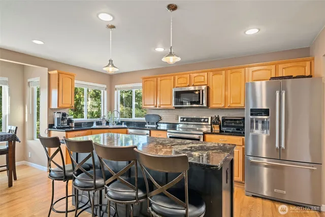 a kitchen with stainless steel appliances granite countertop a stove a refrigerator a kitchen island a table and chairs