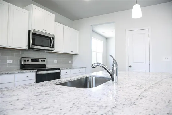 a kitchen with stainless steel appliances granite countertop a stove a microwave and a sink