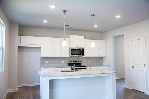 a kitchen with white cabinets and appliances