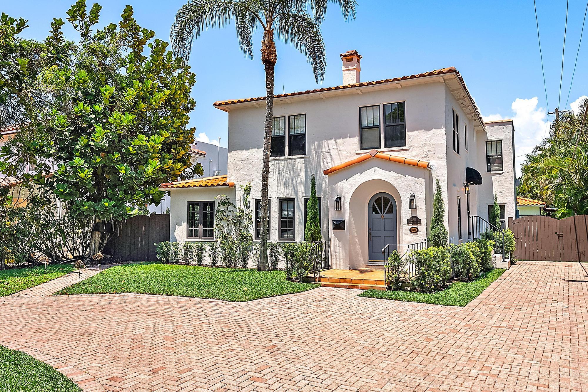 a front view of a house with a yard and potted plants