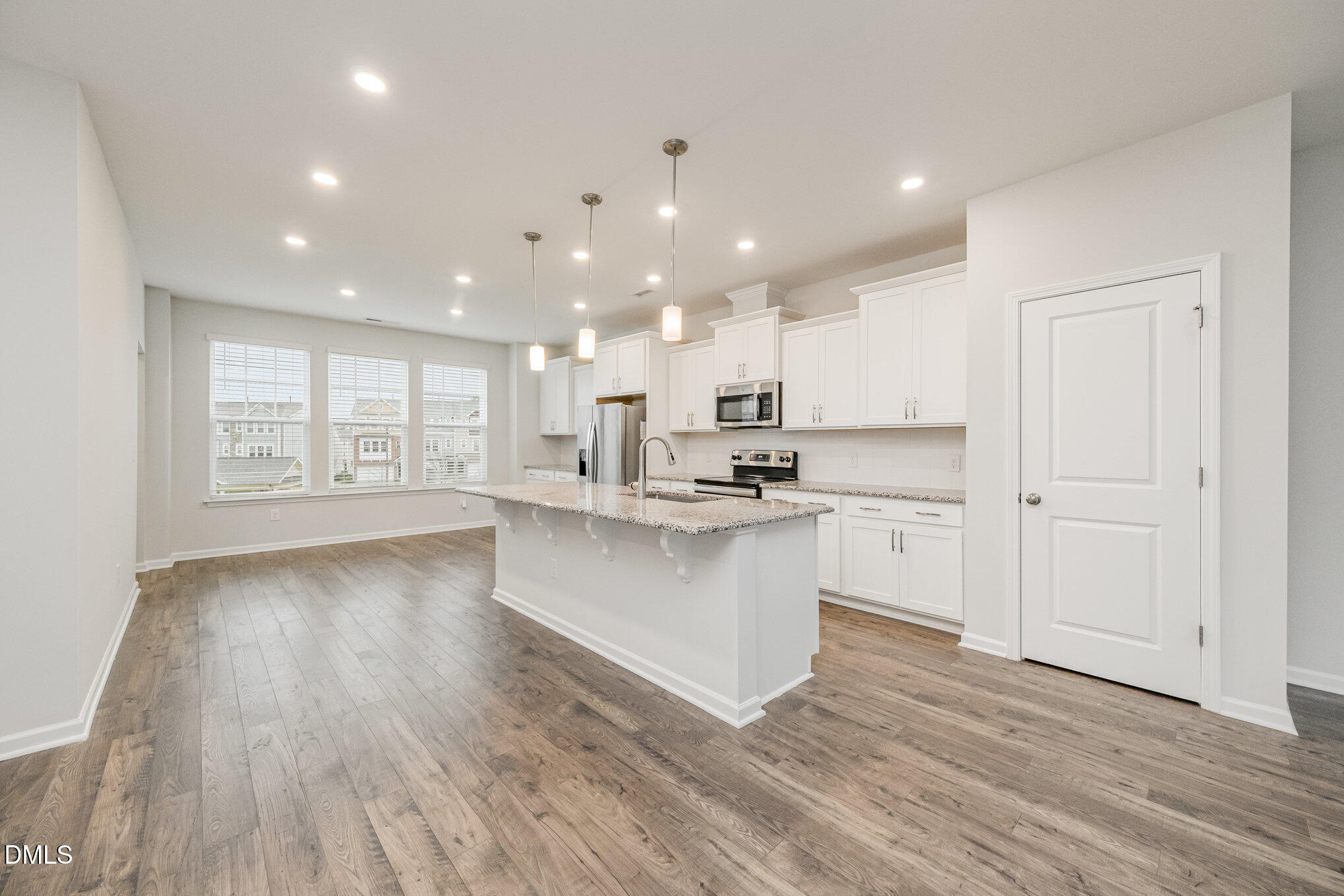 1019 Islip Place Durham, NC 27703 - Photo 3 of 18 a large white kitchen with kitchen island a sink wooden floor white cabinets and a granite counter tops