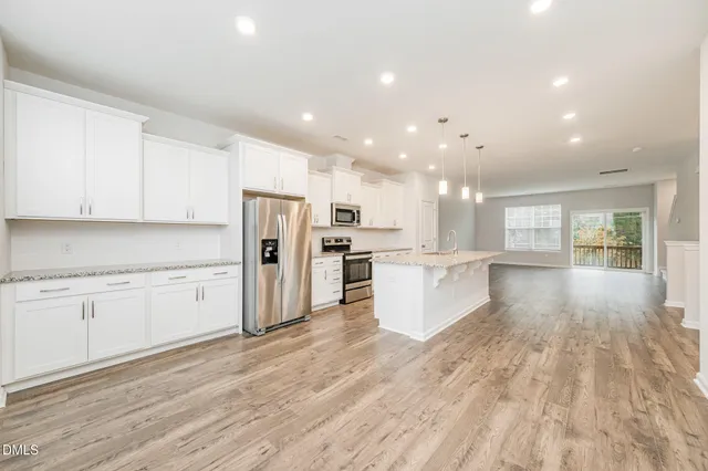 a large kitchen with cabinets wooden floor stainless steel appliances and a window