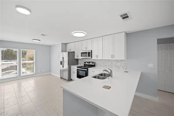 a kitchen with stainless steel appliances a stove a sink a microwave and cabinets