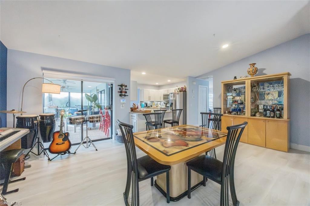 4228 31st Place Southwest Naples, FL 34116 - Photo 13 of 28 a view of a dining room and livingroom with furniture wooden floor a rug a potted plant and a chandelier