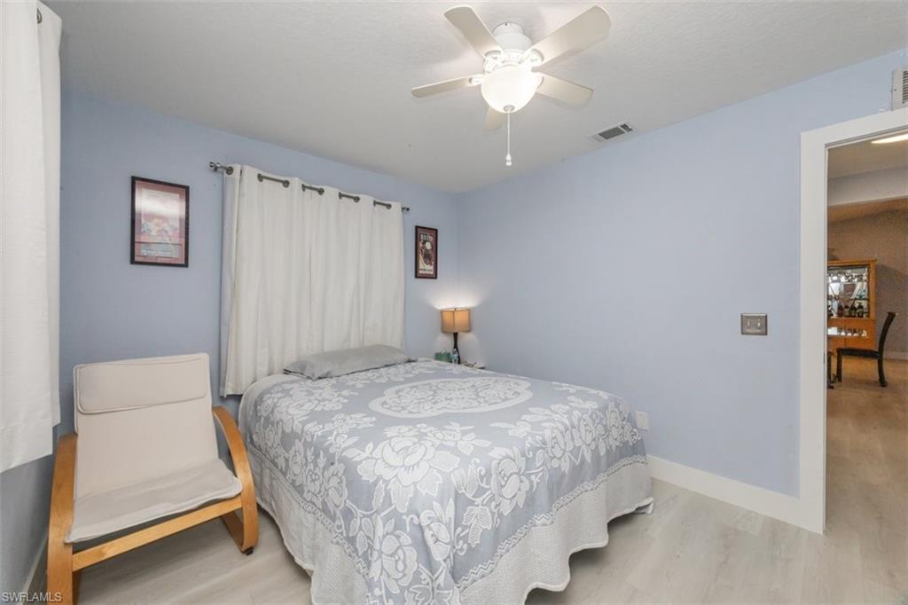 4228 31st Place Southwest Naples, FL 34116 - Photo 19 of 28 a bedroom with a bed and a chandelier