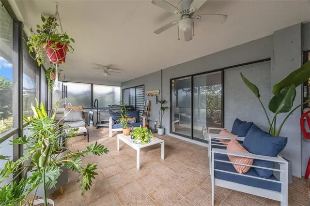 a living room with furniture a floor to ceiling window and a potted plant