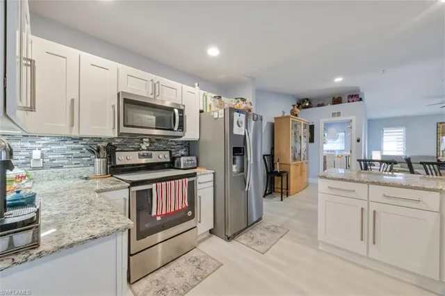 a kitchen with white cabinets sink and stove