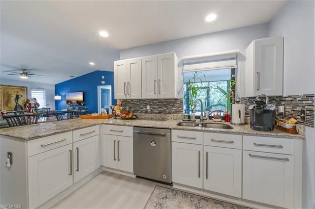 a kitchen with stainless steel appliances granite countertop a stove top oven a sink dishwasher and white cabinets with wooden floor