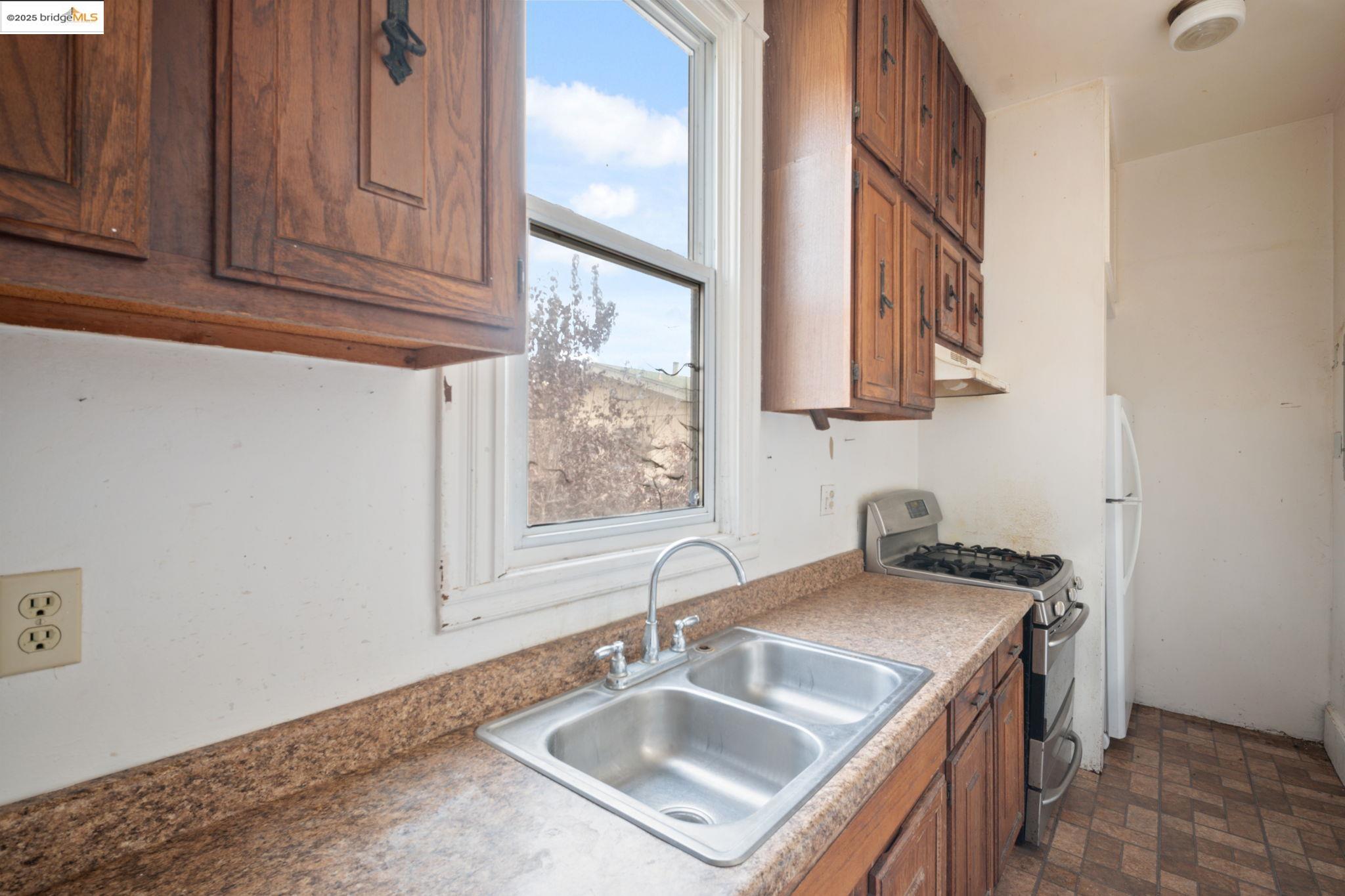 443 Watson Street Monterey, CA 93940 - Photo 14 of 51 Kitchen featuring brown cabinets, stainless steel gas stove, under cabinet range hood, and freestanding refrigerator