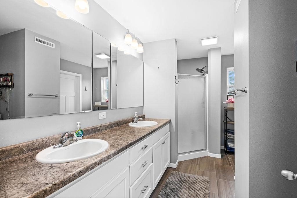 3258 West Tischer Road Duluth, MN 55804 - Photo 10 of 40 Full bath featuring visible vents, a sink, double vanity, and a stall shower