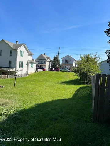 a view of a house with a big yard and large trees
