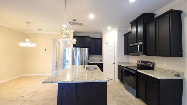 a kitchen with kitchen island granite countertop stainless steel appliances a sink stove and refrigerator