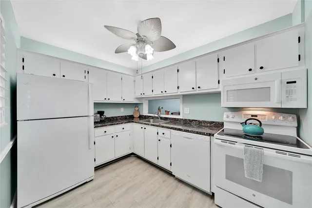 a kitchen with granite countertop white cabinets and white stainless steel appliances