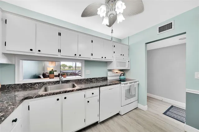 a kitchen with granite countertop white cabinets white appliances and a granite counter tops