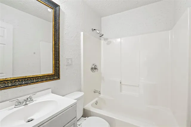 a bathroom with a bathtub shower sink vanity and a toilet