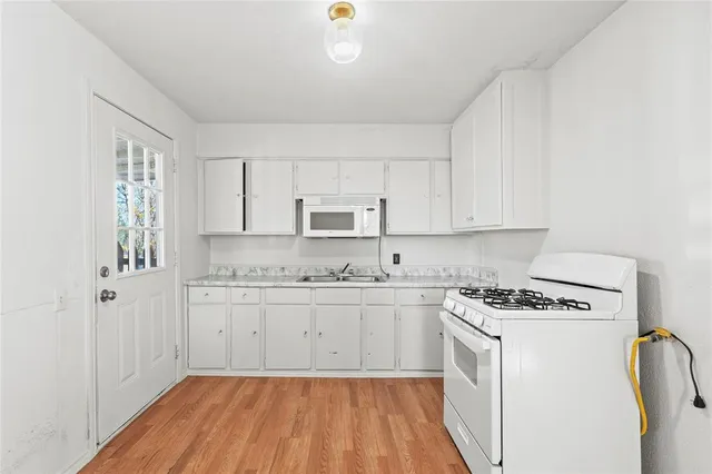 a kitchen with granite countertop white cabinets and white appliances