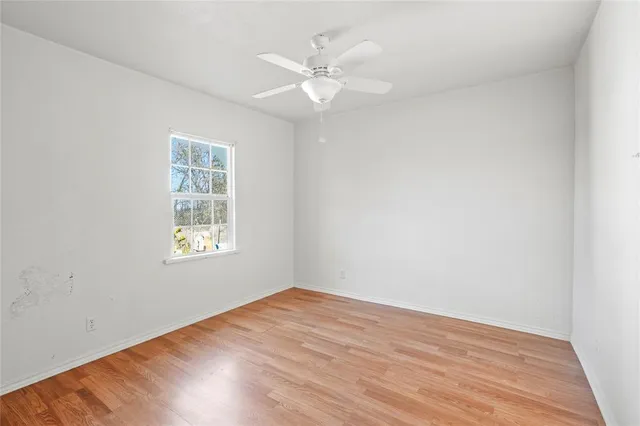 an empty room with a window and a fan