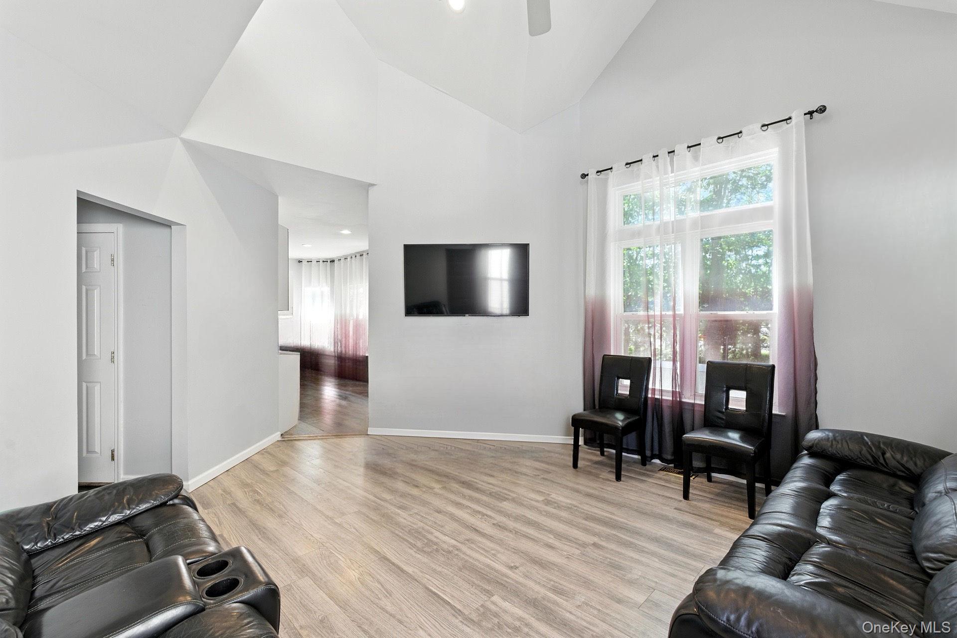 33 Sunflower Ridge Road Centereach, NY 11720 - Photo 7 of 20 Living room featuring high vaulted ceiling, light wood finished floors, and a ceiling fan