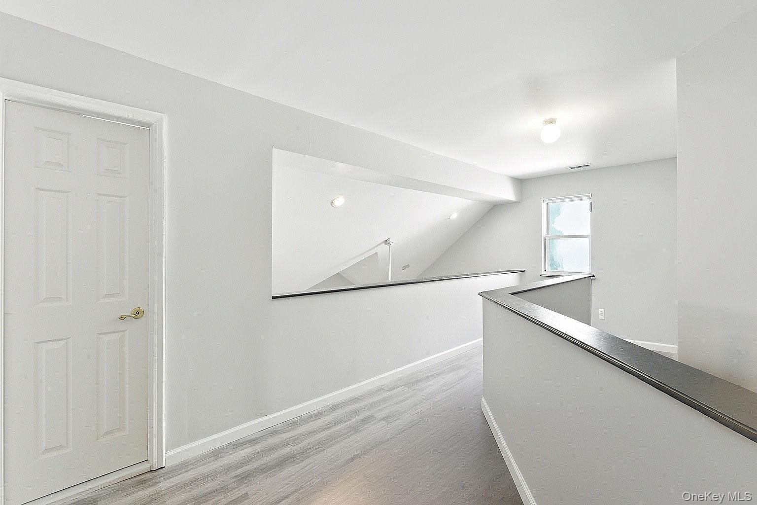 33 Sunflower Ridge Road Centereach, NY 11720 - Photo 8 of 20 Hallway featuring an upstairs landing, light wood-style flooring, and lofted ceiling.