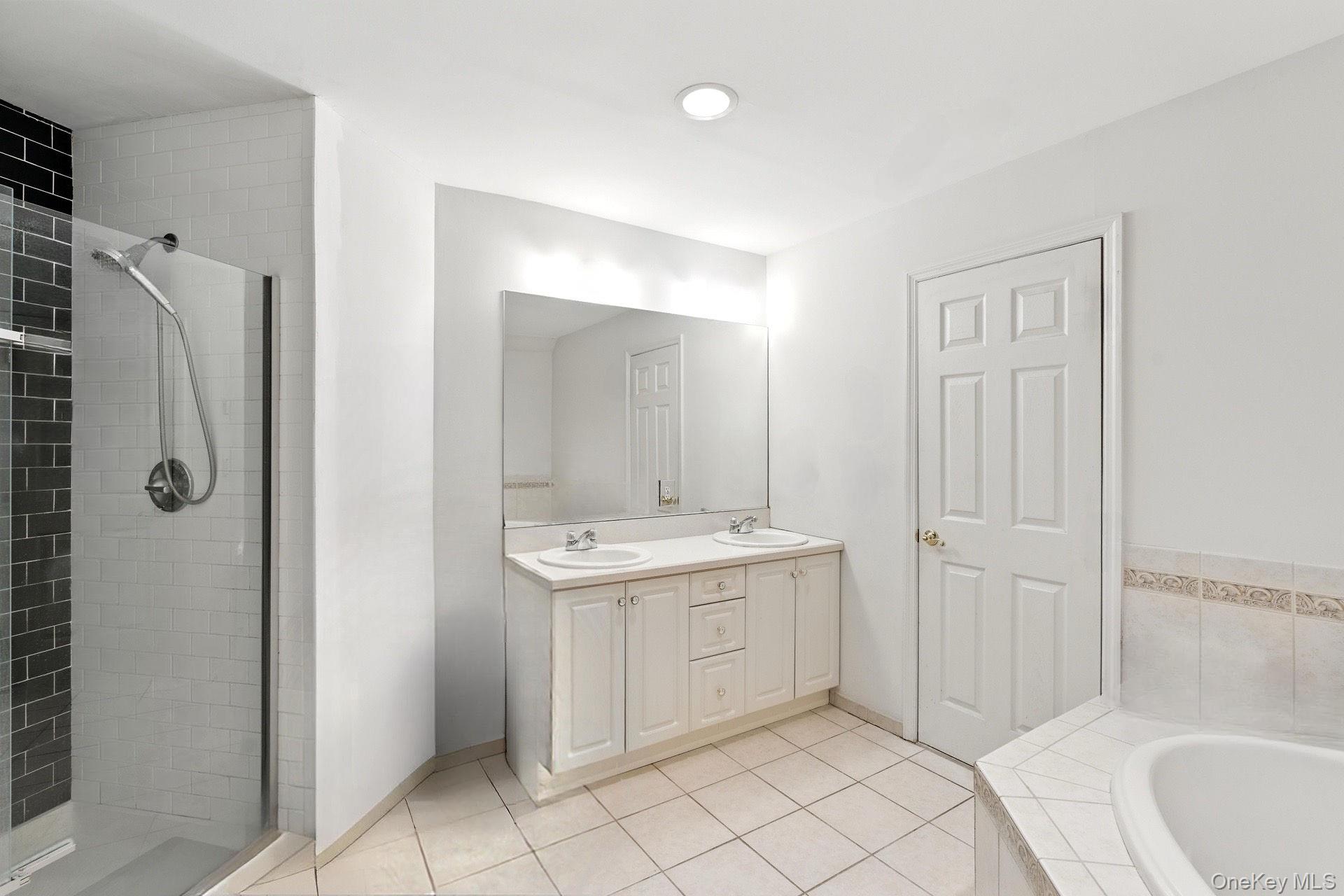 33 Sunflower Ridge Road Centereach, NY 11720 - Photo 10 of 20 Primary bathroom with double vanity, tiled shower, tile patterned floors, and recessed lighting.