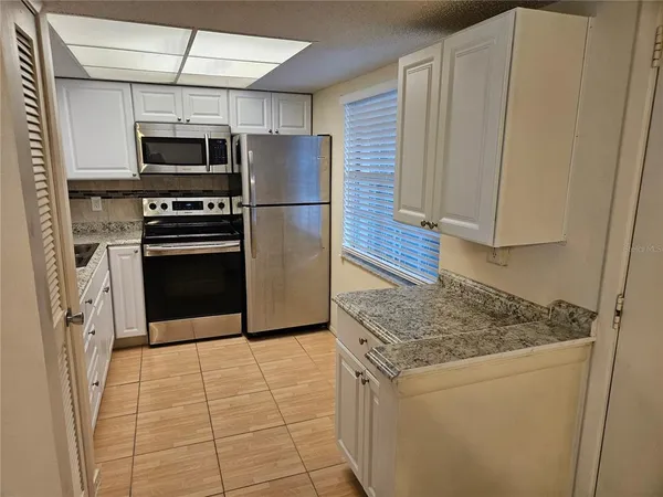 a kitchen with stainless steel appliances granite countertop a refrigerator a stove and a sink