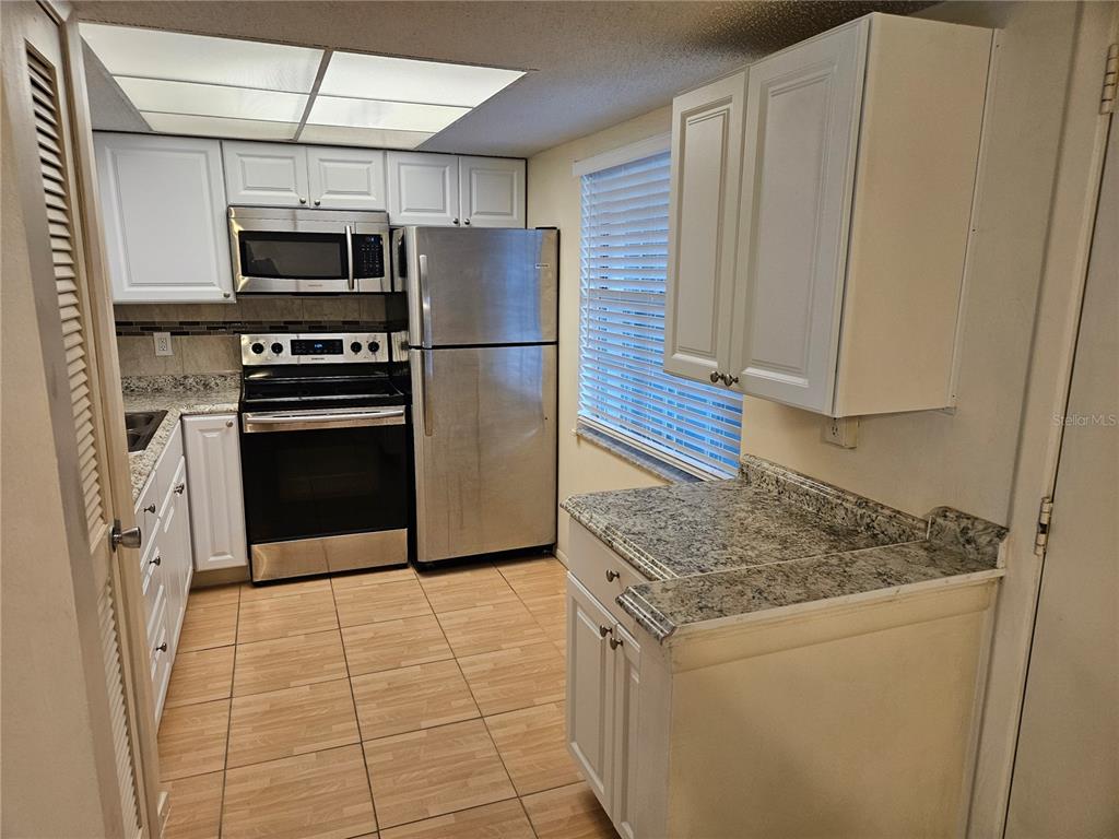 946 Virginia Street, Unit 104 Dunedin, FL 34698 - Photo 4 of 23 a kitchen with stainless steel appliances granite countertop a refrigerator a stove and a sink