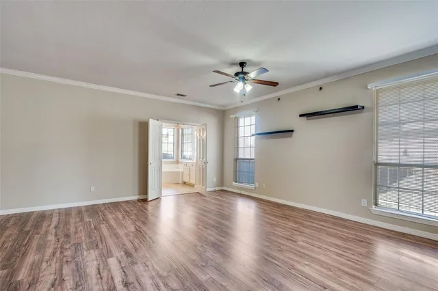 a view of an empty room with a window and wooden floor